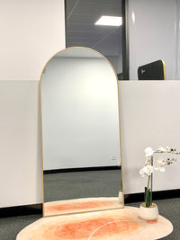 Elegant full-length arch mirror with a gold frame, styled in a modern interior setting